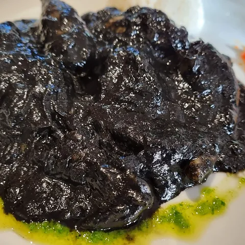 Chipirones en su tinta, con la salsa negra sobre el plato blanco.