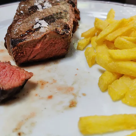 Un corte de chuleta hecho a la parrilla, con patatas fritas.
