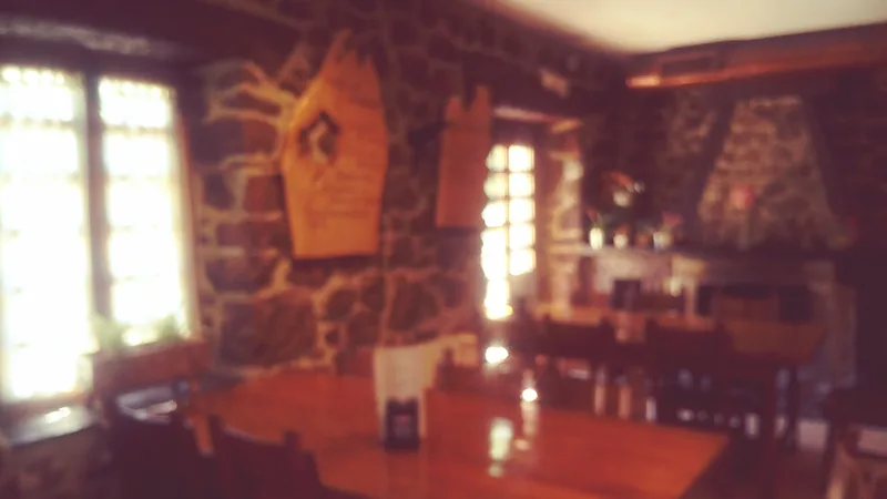 Comedor de paredes de piedra con vigas de madera y mesas puestas.