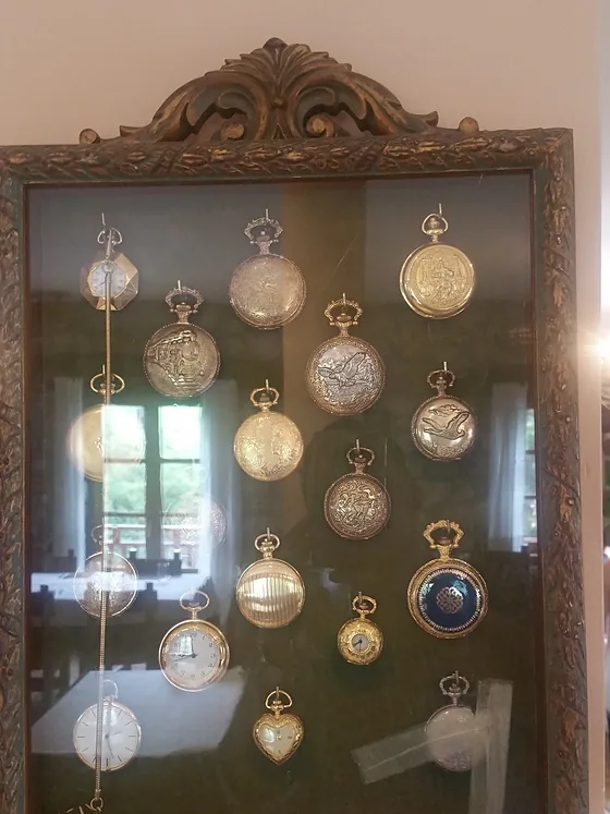 Vitrina de madera con una colección de relojes de bolsillo colgados.